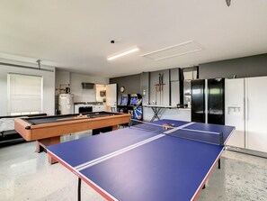 A room with a ping pong table, a pool table, and a kitchen area with appliances. - Beautiful Windsor Palms 4 Bed South Facing Pool 4 Bedroom Villa by RedAwning (Kissimmee)