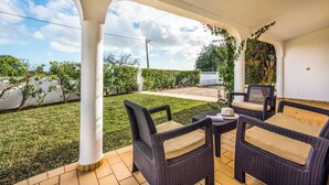 Eine überdachte Terrasse mit Korbmöbeln und Blick auf Garten und Weinberg.