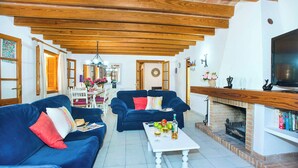A living room with two blue sofas, a white coffee table, and a brick fireplace. - Villa Tanca - Three Bedroom Villa, Sleeps 6 (El Vilà)