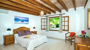 A bedroom with a wooden bed, a nightstand, a desk, a chair, a window with curtains, and a painting on the wall. - Villa Tanca - Three Bedroom Villa, Sleeps 6 (El Vilà)