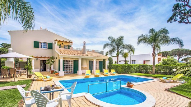 Ein modernes Haus mit Swimmingpool, Sitzgelegenheit im Freien und Palmen.