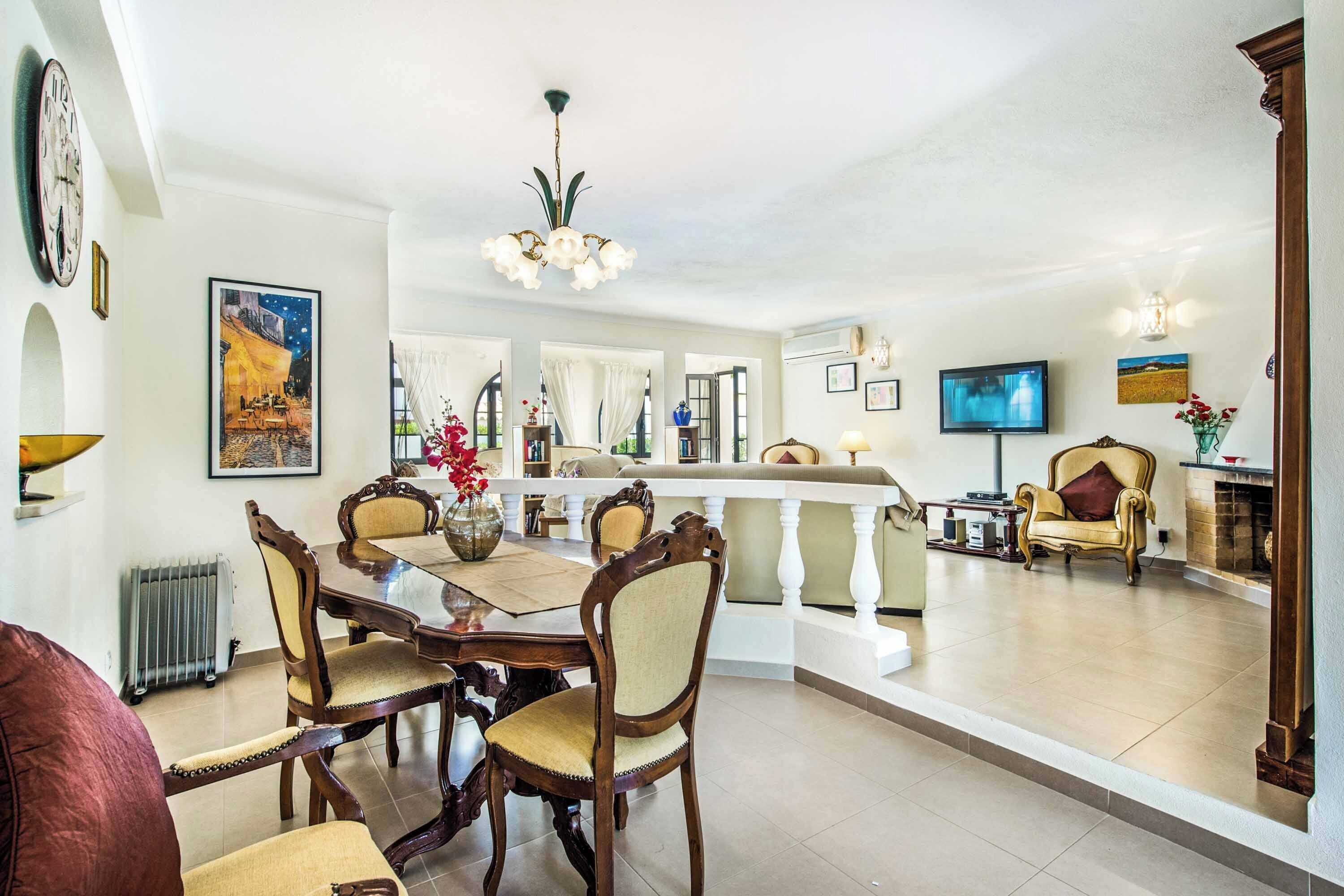 A spacious living area with a dining table, chairs, a TV, and a fireplace.