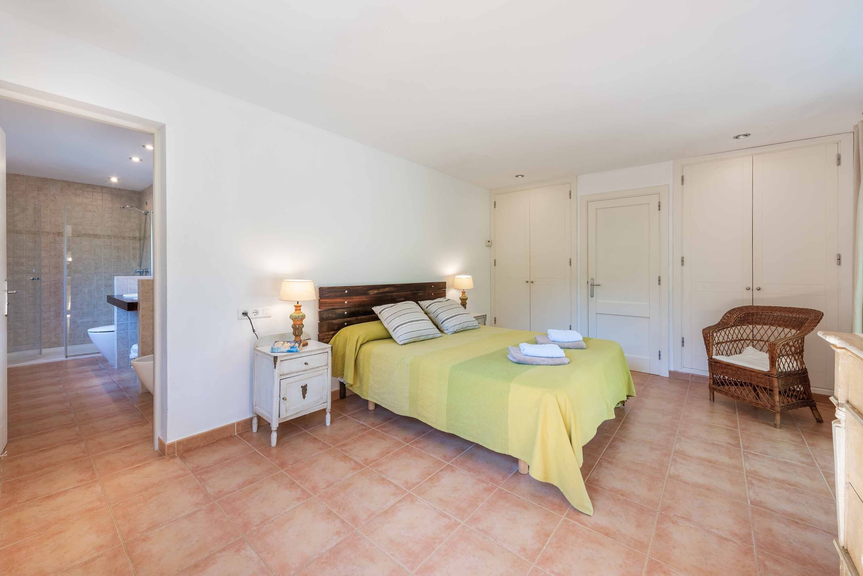 A bedroom with a bed, bedside tables, a chair, and a wardrobe.