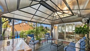 An outdoor patio with a glass table, chairs, and a covered seating area. - 4 bedroom, 2 bath home with covered deck, firepit, fenced yard - with linens! (Ocean View)