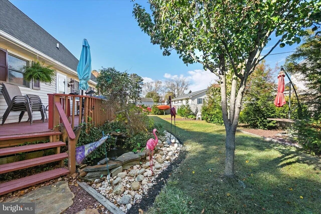 Ein Garten mit Holzterrasse, Baum und Pflanzen, einschließlich Steinen.