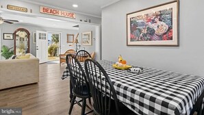 A dining area with a checkered tablecloth, black chairs, and a framed artwork on the wall. - 4 bedroom, 2 bath home with covered deck, firepit, fenced yard - with linens! (Ocean View)