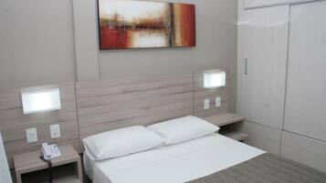 A hotel room with a bed, bedside tables, a phone, and a painting on the wall.