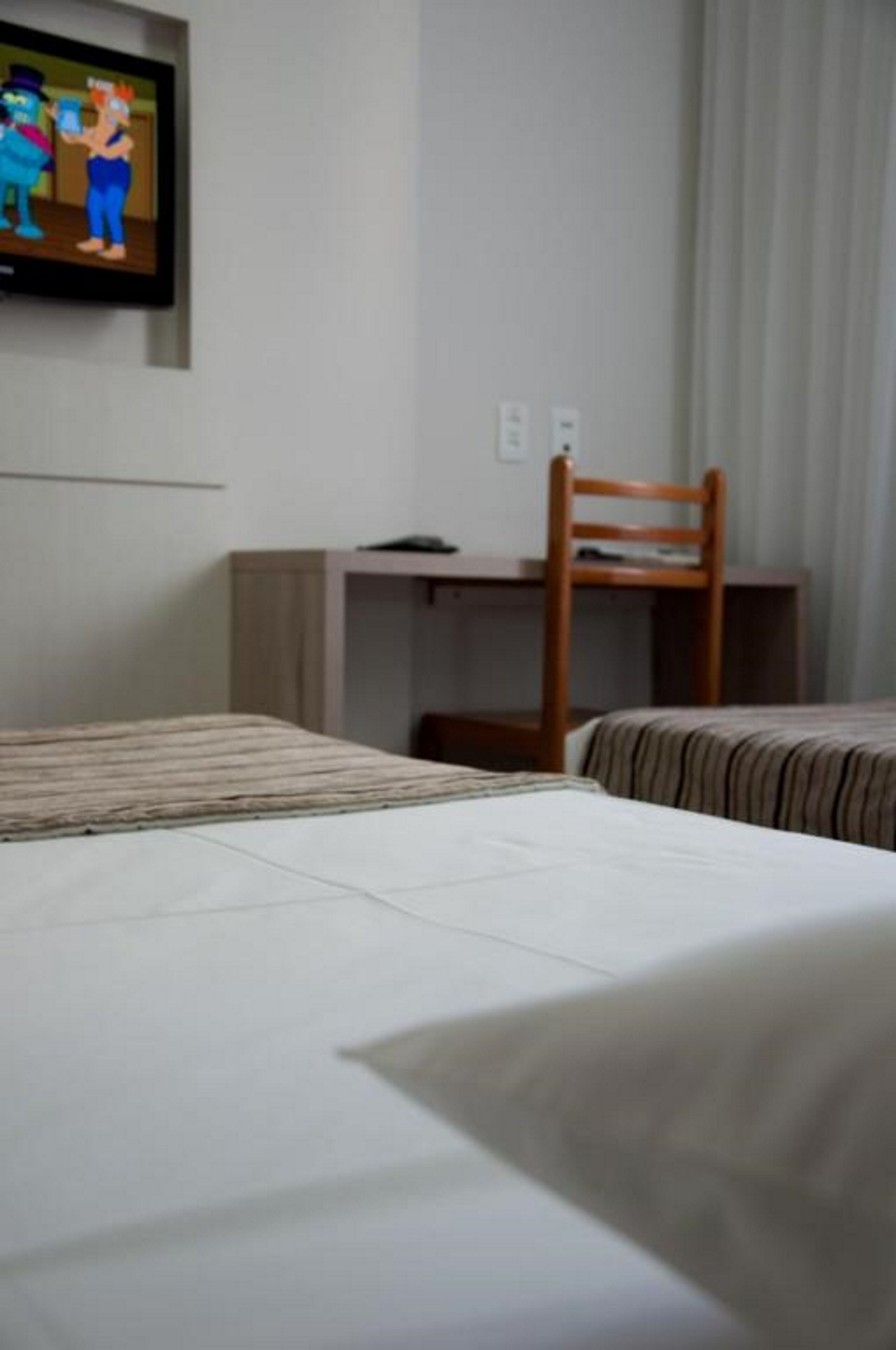 Une chambre d’hôtel avec un lit, un bureau et une chaise.