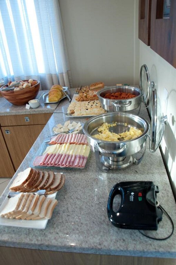 A breakfast buffet with various food items and a kettle on the counter.