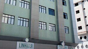 Un edificio de varios pisos con un cartel que indica 'LINHATUR Hotel' y 'PRECISA Farmacia & Manufaktur'.