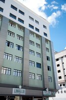 Um edifício de vários andares com uma placa indicando 'LINHATUR Hotel' e 'PRECISA Farmácia & Manufaktur'.
