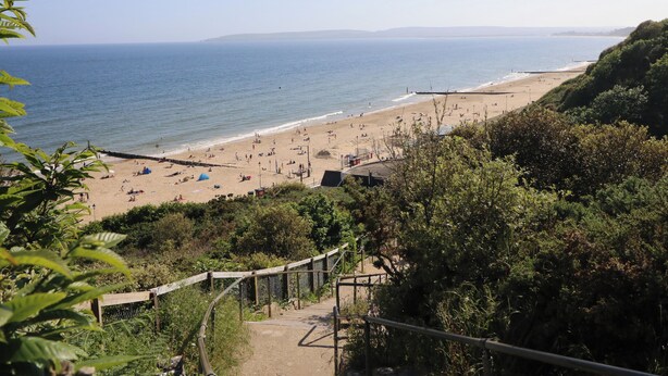 A beach with a wooden walkway leading to the shore.