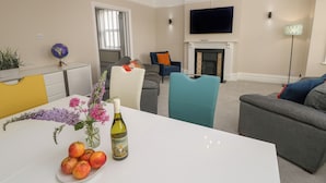 A modern living room with a white table, a sofa, and a television.