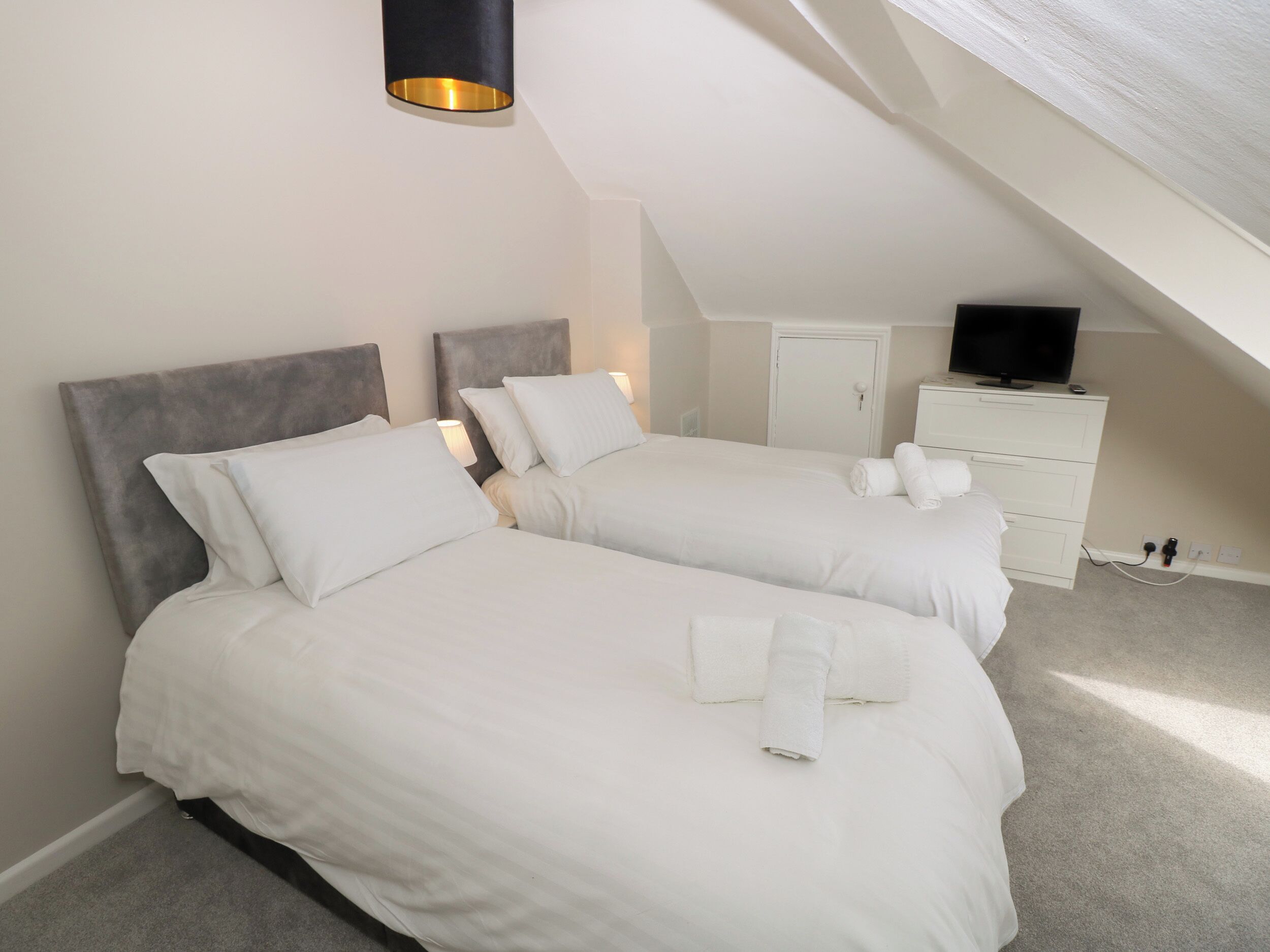 A bedroom with two beds, a TV, and a desk.