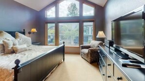 Un dormitorio con una cama grande, un televisor, una silla y una ventana con vistas al exterior.