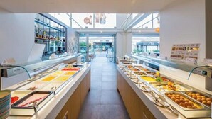 Zona de bufé con varias estaciones de comida y vista despejada al exterior.