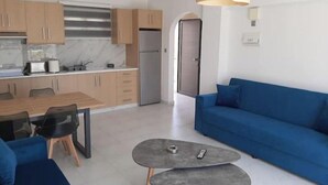 Una cocina moderna con armarios de madera, un refrigerador de acero inoxidable y una zona de comedor con mesa y sillas.