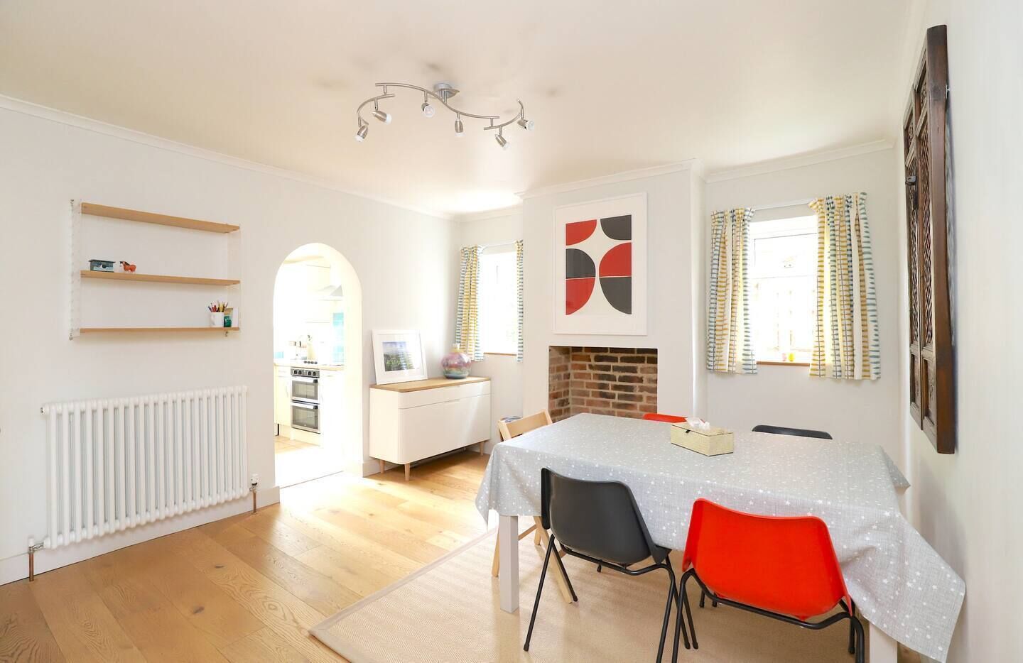 Una cocina moderna con armarios blancos, un comedor con mesa y sillas, y una chimenea.