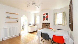 A modern kitchen with white cabinetry, a dining area with a table and chairs, and a fireplace.