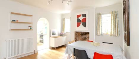 Una cocina moderna con armarios blancos, un comedor con mesa y sillas, y una chimenea.
