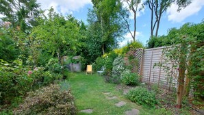 A garden with a lawn, stepping stones, a wooden fence, and a shed.