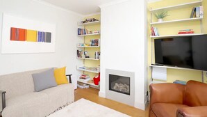 A living room with a sofa, a fireplace, a bookshelf, and a TV.