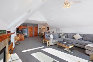 A spacious living area with a high ceiling, a fireplace, a sofa set, and a dining area with wooden furniture. - 3 Bedroom Condo on Main Street in Breckenridge - Pool, Hot Tubs, Fitness Center & More! (Breckenridge)