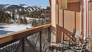 A balcony with a view of snow-covered mountains, a table with chairs, and a glass table. - 3 Bedroom Condo on Main Street in Breckenridge - Pool, Hot Tubs, Fitness Center & More! (Breckenridge)