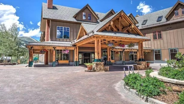 A large building with a covered entrance, multiple windows, and a brick pathway leading to the entrance. - 3 Bedroom Condo on Main Street in Breckenridge - Pool, Hot Tubs, Fitness Center & More! (Breckenridge)