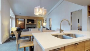 A modern kitchen with a large island, built-in oven, and a double sink.