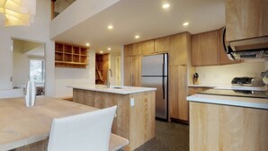 A modern kitchen with wooden cabinets, a stainless steel refrigerator, and a central island with a sink.