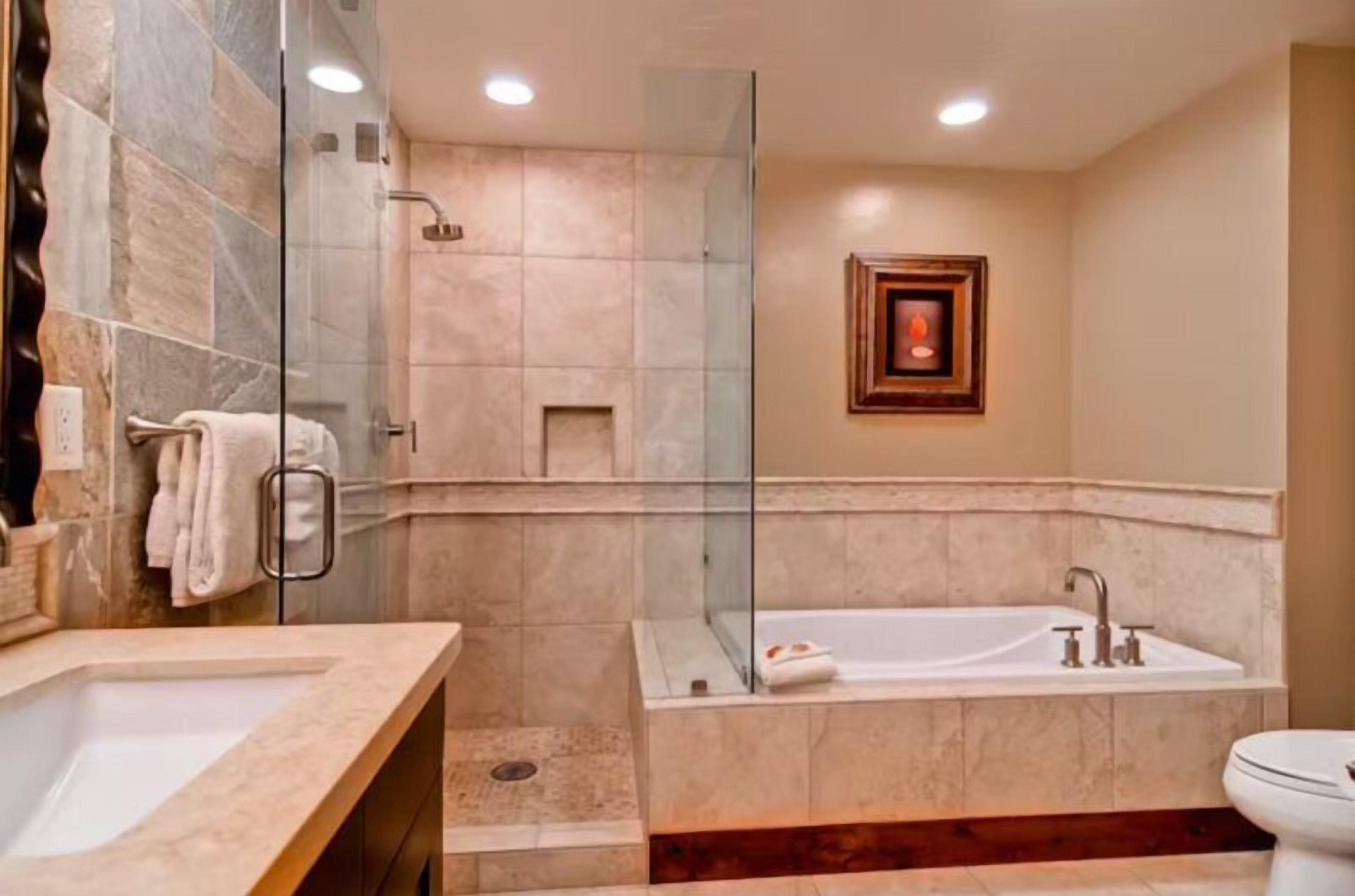 Un baño moderno con ducha envuelta en vidrio, bañera independiente y lavamanos separado.