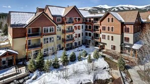 Un hôtel à plusieurs étages doté de balcons, avec une piste de ski en arrière-plan et un sol recouvert de neige.
