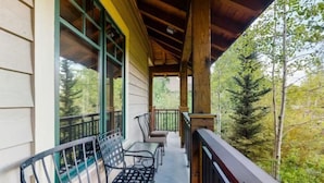 A covered porch with a wooden ceiling, a railing, and a view of trees. - 2 Bedroom Luxury Condo on Main Street at Maggie Pond - Walk to Lift! (Breckenridge)