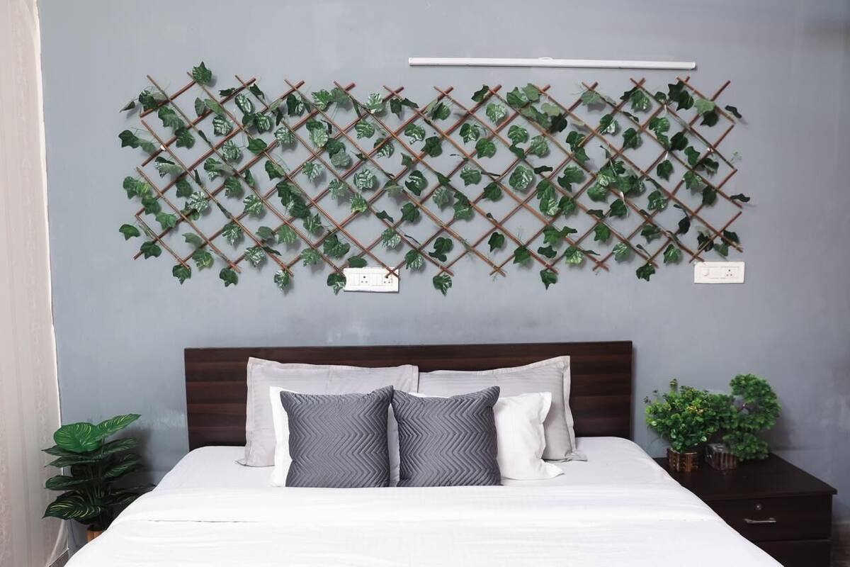 A bedroom with a bed, a headboard, a wall-mounted plant grid, and a nightstand with a plant.