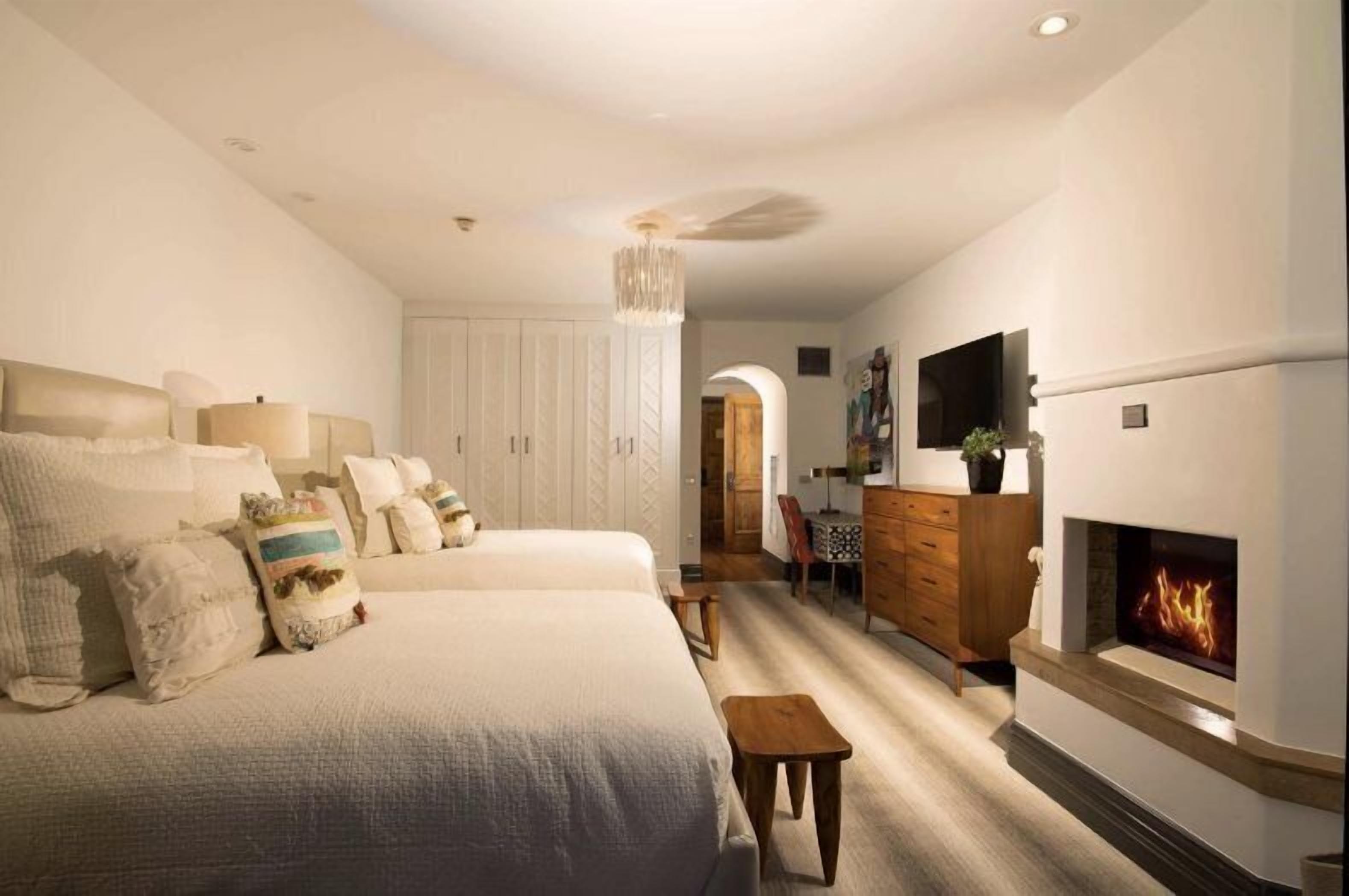 Une chambre avec deux lits, une commode, une télévision et une cheminée.