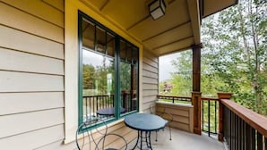 A covered porch with two metal tables and chairs, a wooden railing, and large windows. - Water House Luxury 2 Bedroom on Main Street - Walk to Quicksilver Lift! (Breckenridge)