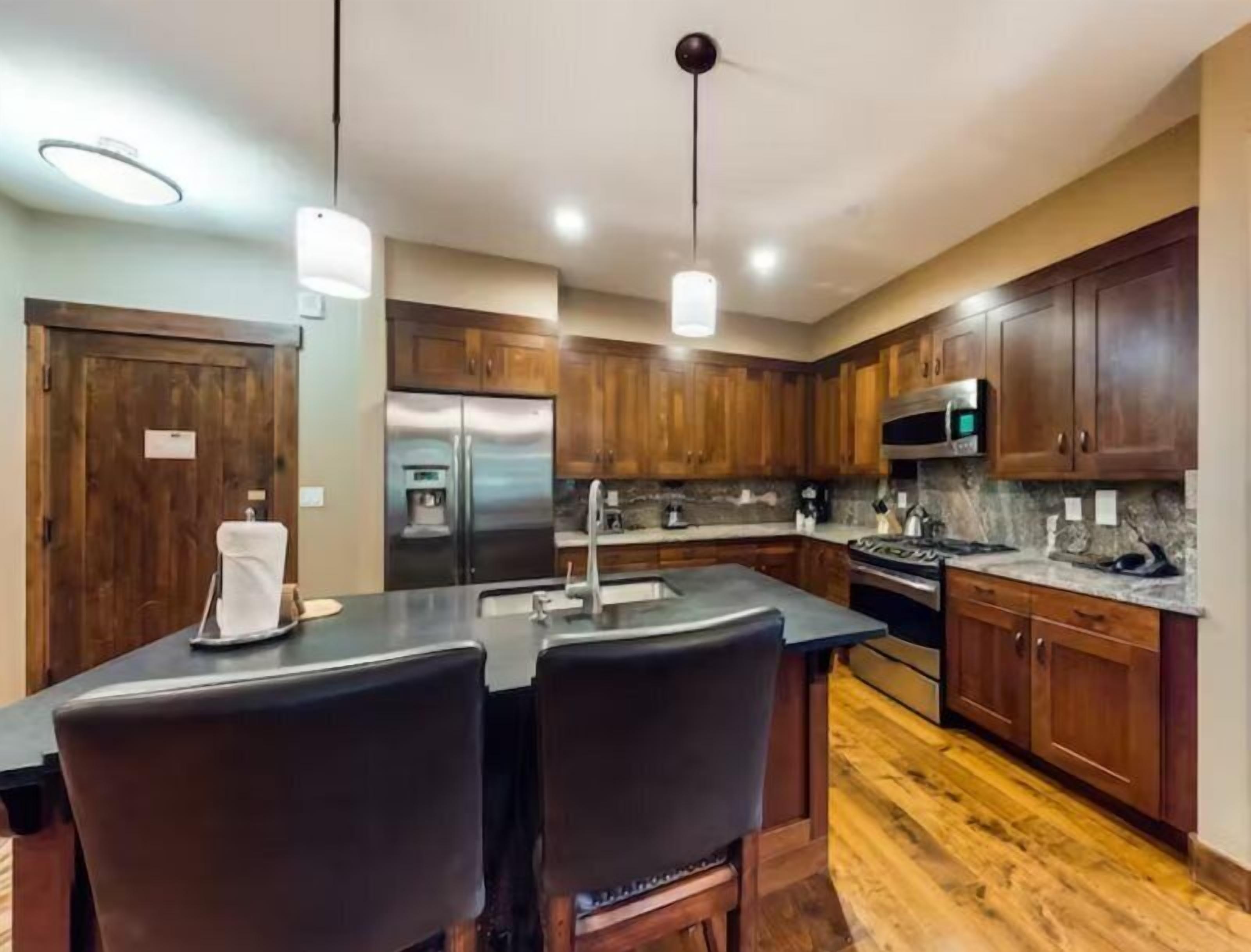 A modern kitchen with wooden cabinets, stainless steel appliances, and a central island with bar stools.