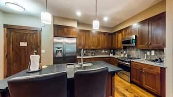 A modern kitchen with wooden cabinets, stainless steel appliances, and a central island with bar stools.