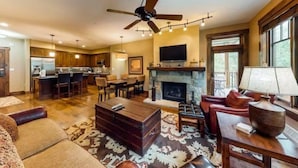 A spacious living room with a fireplace, a dining area, and a kitchen. - Water House Luxury 2 Bedroom on Main Street - Walk to Quicksilver Lift! (Breckenridge)