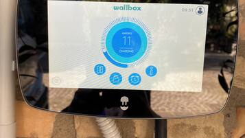 A wallbox charging station with a digital display indicating 11 Amperes of charging.