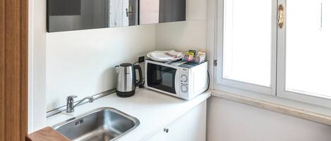 A compact kitchen with a sink, microwave, and cabinets.