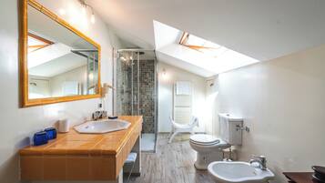 A modern bathroom with a large mirror, dual sinks, a shower, and a skylight.