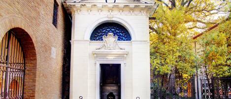 Un edificio blanco con una entrada central, un arco decorativo y un pequeño frontón sobre la puerta.