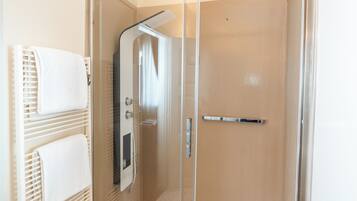 Un bagno moderno con cabina doccia in vetro, una vasca da bagno bianca e un portasciugamani con asciugni piegati.
