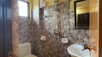 A bathroom with a toilet, a shower, and a sink.