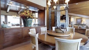 Zona pranzo con un tavolo rotondo, sedie, un vaso con fiori e un camino in pietra.