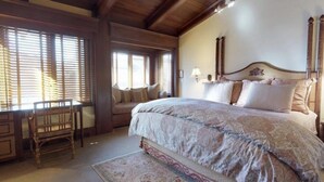 Una camera da letto con un grande letto, una testiera in legno e una finestra con persiane.