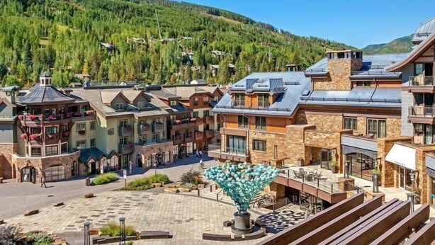 Un hotel con varias construcciones, un patio central y montañas al fondo.