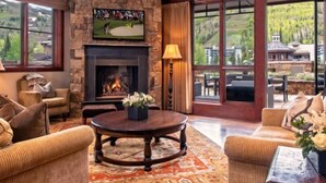 Una sala de estar acogedora con chimenea, asientos cómodos y un ventanal con vistas panorámicas.